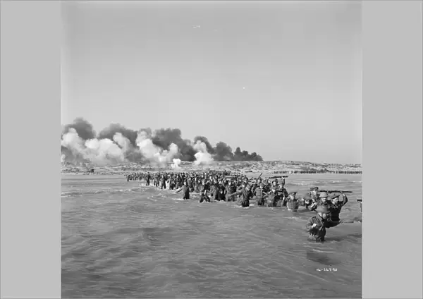 British troops walk into the water to try and board one of the small boats