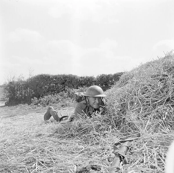Corporal Tubby Bins hides behind a hay bale