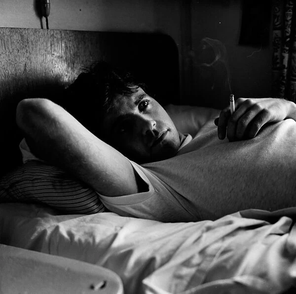 Jim smoking a cigarette in bed