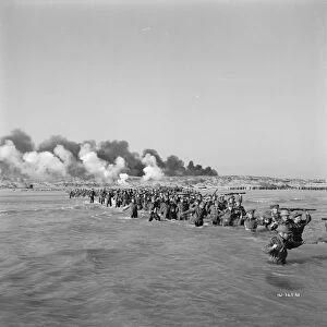 British troops walk into the water to try and board one of the small boats