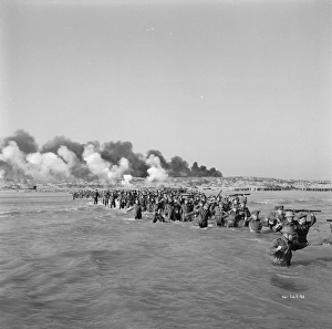 British troops walk into the water to try and board one of the small boats