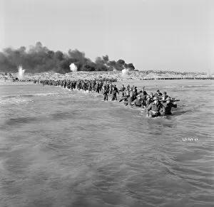 Bombardment Collection: British troops walk into the water to try and board one of the small boats